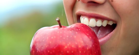 Zahnarzt Yoav Sandler in Mannheim, junge Frau beißt in einen roten Apfel